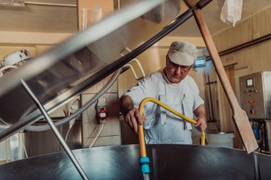 A cheese makser working in the industry on various machines with the help of which cheese is processed. Small business concept. 