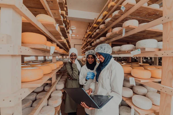 Arab business partners checking the quality of cheese in the industry and enter data into a laptop. Small business concept.