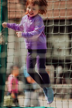 A little girl playing in the park. The concept of family socializing in the park. A girl swings on a swing, plays creative games. 