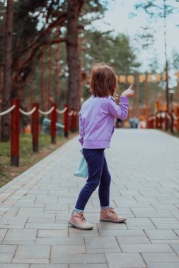 A little girl playing in the park. The concept of family socializing in the park. A girl swings on a swing, plays creative games. 