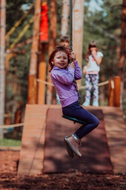 A little girl playing in the park. The concept of family socializing in the park. A girl swings on a swing, plays creative games. 