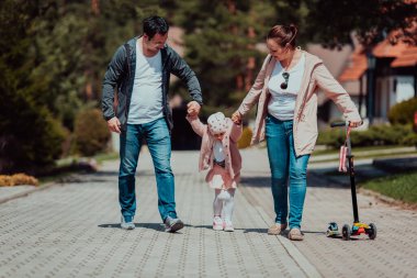 Family fun in the park. Happy family spending time in park and playing with their daughter. 