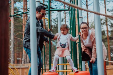 Family fun in the park. Happy family spending time in park and playing with their daughter. 