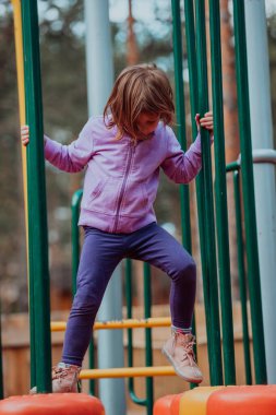 A little girl playing in the park. The concept of family socializing in the park. A girl swings on a swing, plays creative games. 