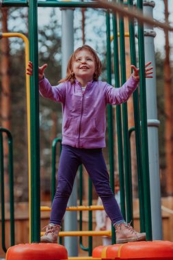 A little girl playing in the park. The concept of family socializing in the park. A girl swings on a swing, plays creative games. 