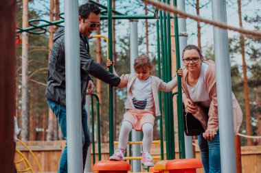 Family fun in the park. Happy family spending time in park and playing with their daughter. 