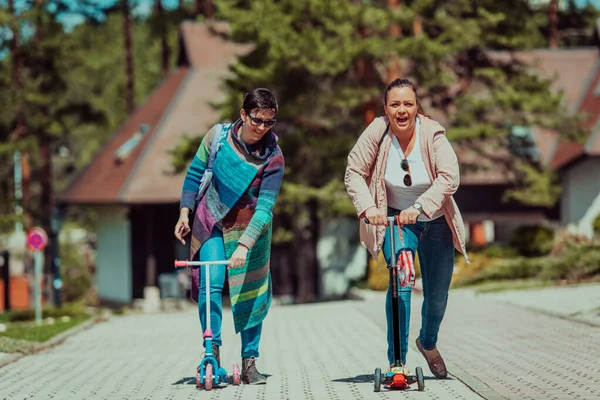 Duas Mulheres Divertindo Parque Enquanto Montam Uma Scooter — Fotografia de Stock