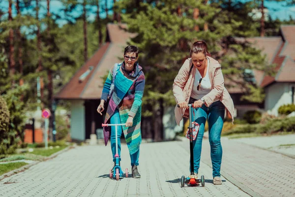 Two Women Having Fun Park While Riding Scooter — Stock fotografie