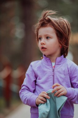 A little girl playing in the park. The concept of family socializing in the park. A girl swings on a swing, plays creative games. 