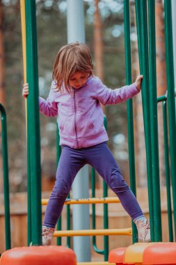 A little girl playing in the park. The concept of family socializing in the park. A girl swings on a swing, plays creative games. 