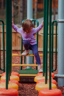 Parkta oynayan küçük bir kız. Ailenin parkta sosyalleşme konsepti. Bir kız salıncakta sallanıyor, yaratıcı oyunlar oynuyor.. 
