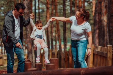 Family fun in the park. Happy family spending time in park and playing with their daughter. 