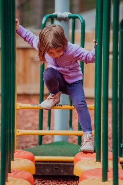 A little girl playing in the park. The concept of family socializing in the park. A girl swings on a swing, plays creative games. 