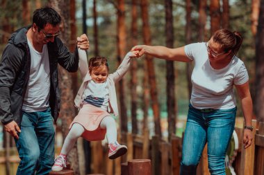 Family fun in the park. Happy family spending time in park and playing with their daughter. 
