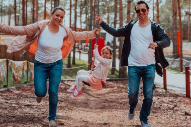 Family fun in the park. Happy family spending time in park and playing with their daughter. 