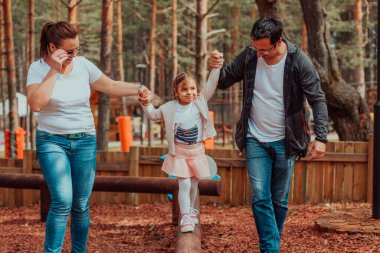 Family fun in the park. Happy family spending time in park and playing with their daughter. 