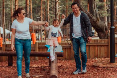 Family fun in the park. Happy family spending time in park and playing with their daughter. 