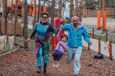 Family fun in the park. Happy family spending time in park and playing with their daughter. 