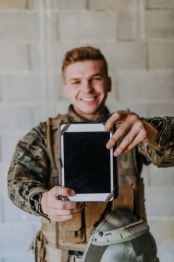 Asker eski tuğla duvara karşı tablet bilgisayar kullanıyor.