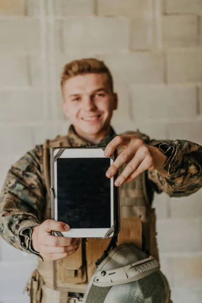 士兵在旧砖墙上使用平板电脑 — 图库照片