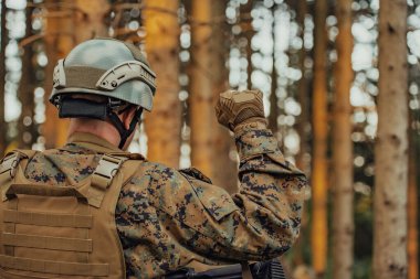 Çağdaş savaş subayı, manga ormanı çevresi için sessizce emir vermek üzere taktik el işaretleri gösteriyor..