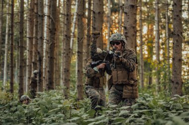 Bir grup modern savaş askeri tehlikeli uzak orman bölgelerinde savaşıyor. Bir grup asker modern silahlarla düşman hattında savaşıyor. Savaş ve askerlik kavramı.