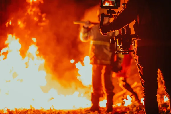 燃える森の中で仕事をしながら消防士を記録するカメラのためのプロの機器と安定性を持つカメラマン — ストック写真