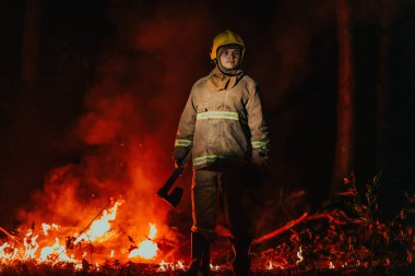 İtfaiyeci iş başında. Güçlü yangınlarla çevrili tehlikeli orman bölgelerinde itfaiyeci. İtfaiye teşkilatının işi kavramı.