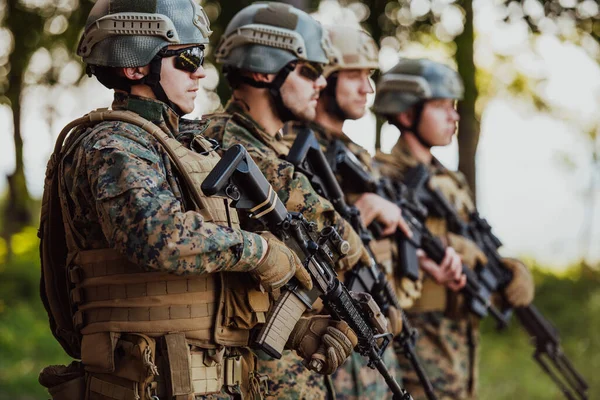 Soldier fighters standing together with guns. Group portrait of US army elite members, private military company servicemen, anti terrorist squad.