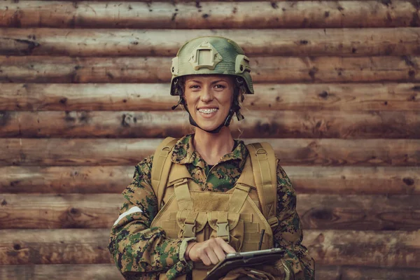 女兵在营地的旧木墙上使用平板电脑 — 图库照片