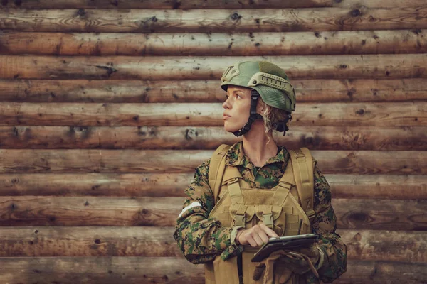 女兵在营地的旧木墙上使用平板电脑 — 图库照片