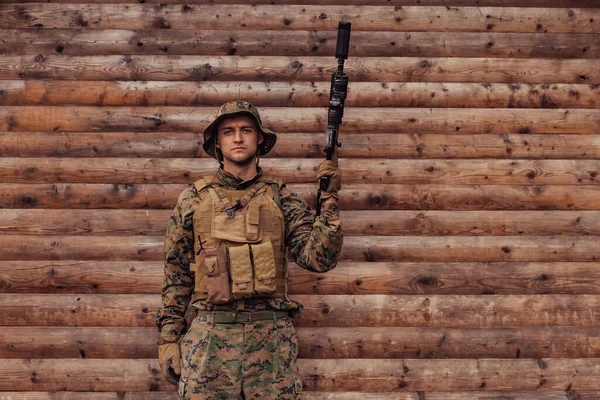 Elinde Tüfekle Üniformalı Bir Asker Ahşap Bir Duvarın Önünde Duruyor — Stok fotoğraf