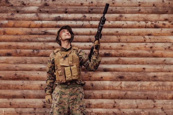 Egy Egyenruhás Katona Puskával Kezében Egy Fafal Előtt Áll Egy — Stock Fotó