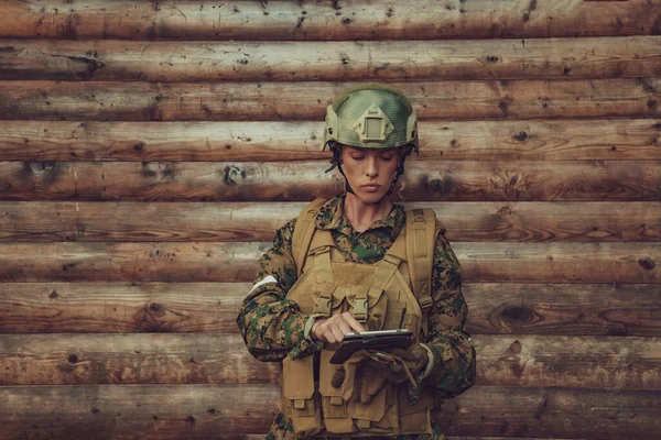 Женщина Солдат Использующая Планшетный Компьютер Против Старой Деревянной Стены Лагере — стоковое фото