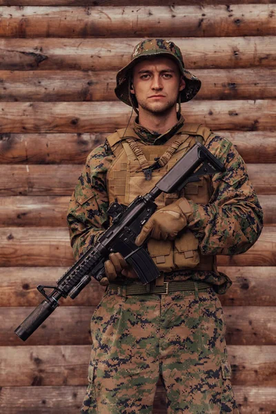 Żołnierz Mundurze Strzelbą Ręku Stoi Przed Drewnianą Ścianą Żołnierz Strzeże — Zdjęcie stockowe