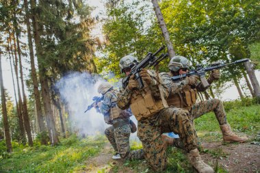 Bir grup modern savaş askeri tehlikeli uzak orman bölgelerinde savaşıyor. Bir grup asker modern silahlarla düşman hattında savaşıyor. Savaş ve askerlik kavramı.