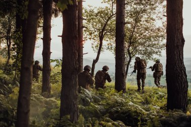 Bir grup modern savaş askeri tehlikeli uzak orman bölgelerinde savaşıyor. Bir grup asker modern silahlarla düşman hattında savaşıyor. Savaş ve askerlik kavramı.