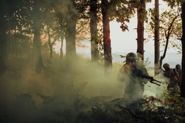 Bir grup modern savaş askeri tehlikeli uzak orman bölgelerinde savaşıyor. Bir grup asker modern silahlarla düşman hattında savaşıyor. Savaş ve askerlik kavramı.