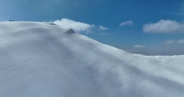 Hava, yükselen, insansız hava aracı, yapraksız ağaçların üzerinden, karlı bir dağın tepesinde, güneşli bir günde, kışın ıssız bir yerde. Yüksek kalite 4k görüntü