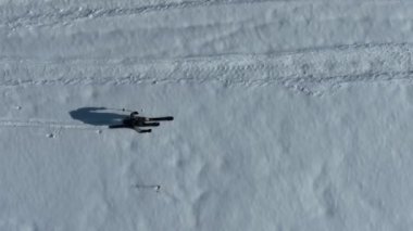 Kros kayakçısı kışın karla kaplı bir orman arazisinde bir patikadan aşağı doğru yürür. Hava aracı izleme görüntüsü. Yüksek kalite 4k görüntü