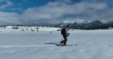 Kros kayakçısı kışın karla kaplı bir orman arazisinde bir patikadan aşağı doğru yürür. Hava aracı izleme görüntüsü. Yüksek kalite 4k görüntü