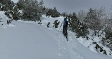 Kışın taze kar mevsiminde dağlarda kameranın önünden geçen hava kayaklı adam. Deri yokuşunda bir sıra halinde kayak turu. Toz günü. kayak tatili konsepti. Yüksek kalite 4k