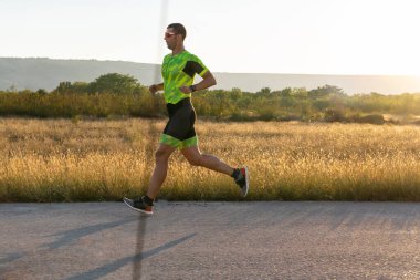 Sabahın erken saatlerinde profesyonel kıyafetlerle koşan triatloncu, maratona hazırlanıyor, spora ve bir maratonun mücadelesine hazırlanıyor.