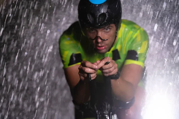彼は夜を通して循環し 次のマラソンのために自分自身を準備し 雨を勇敢トライアスロン 手前のぼやけた雨滴と奥の暗い雰囲気が加わります — ストック写真