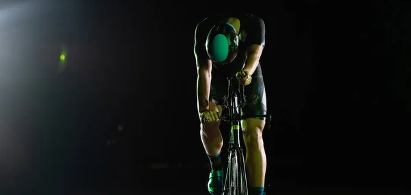 一位三项全能运动员在漆黑的夜晚骑着他的自行车 努力为马拉松做准备 黑暗和他的自行车的灯光之间的反差产生了一种戏剧感 凸显了 — 图库照片