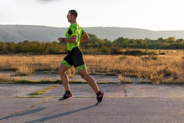 Sabahın erken saatlerinde profesyonel kıyafetlerle koşan triatloncu, maratona hazırlanıyor, spora ve bir maratonun mücadelesine hazırlanıyor.