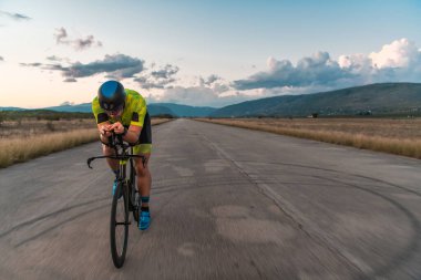  Gün batımında bisiklet süren bir triatloncu, maratona hazırlanıyor. Gökyüzünün sıcak renkleri kararlı ve odaklanmış çabaları için güzel bir zemin sağlar.
