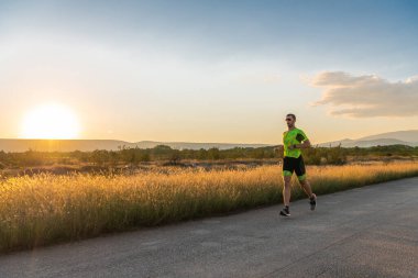 Sabahın erken saatlerinde profesyonel kıyafetlerle koşan triatloncu, maratona hazırlanıyor, spora ve bir maratonun mücadelesine hazırlanıyor.