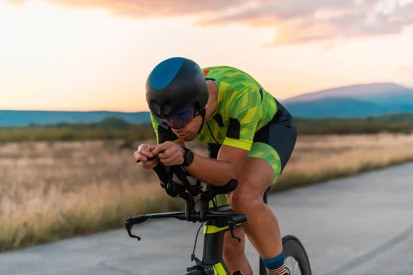 Close up photo of triathlete riding his bicycle during sunset, preparing for a marathon. The warm colors of the sky provide a beautiful backdrop for his determined and focused effort