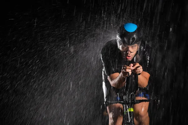 彼は夜を通して循環し 次のマラソンのために自分自身を準備し 雨を勇敢トライアスロン 手前のぼやけた雨滴と奥の暗い雰囲気が加わります — ストック写真